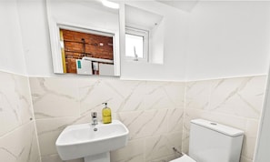 Un baño con lavamanos blanco, espejo y ventana.