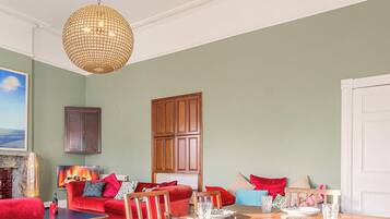 A living room with a red sofa, wooden dining table, and a chandelier.