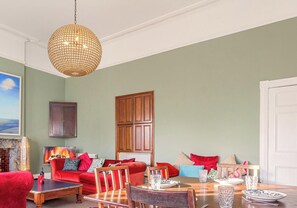 Ein Wohnzimmer mit rotem Sofa, Holzesstisch und einer Chandelier.