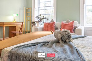 Un lit bien fait, avec une literie à motifs, une tête de lit en bois, un bureau avec une lampe, une chaise et une fenêtre donnant sur un beau paysage.