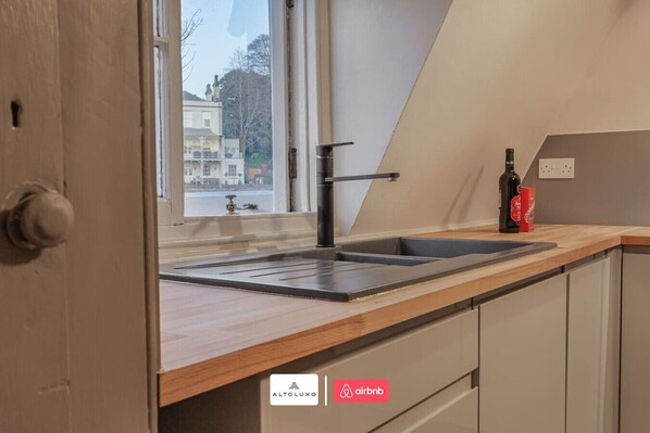 Une cuisine au design moderne, équipée d’un évier, d’une fenêtre et offrant une vue sur l’extérieur.