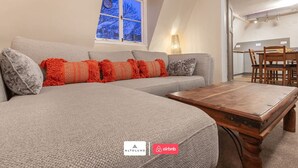 Una sala moderna con un sofá seccional gris, una mesa de centro de madera y un comedor con sillas de madera.