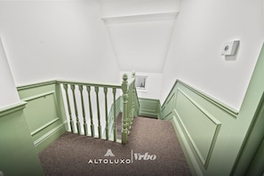 A staircase with green railings and white walls.