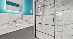 A bathroom with a white sink, a glass shower enclosure, and a mirror with a teal accent wall. - 31A|Stylish Kingswood Retreat for Couples & Pros (Kingswood)