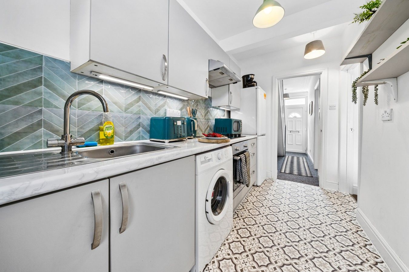 A modern kitchen with a built-in washing machine, a microwave, and a toaster.