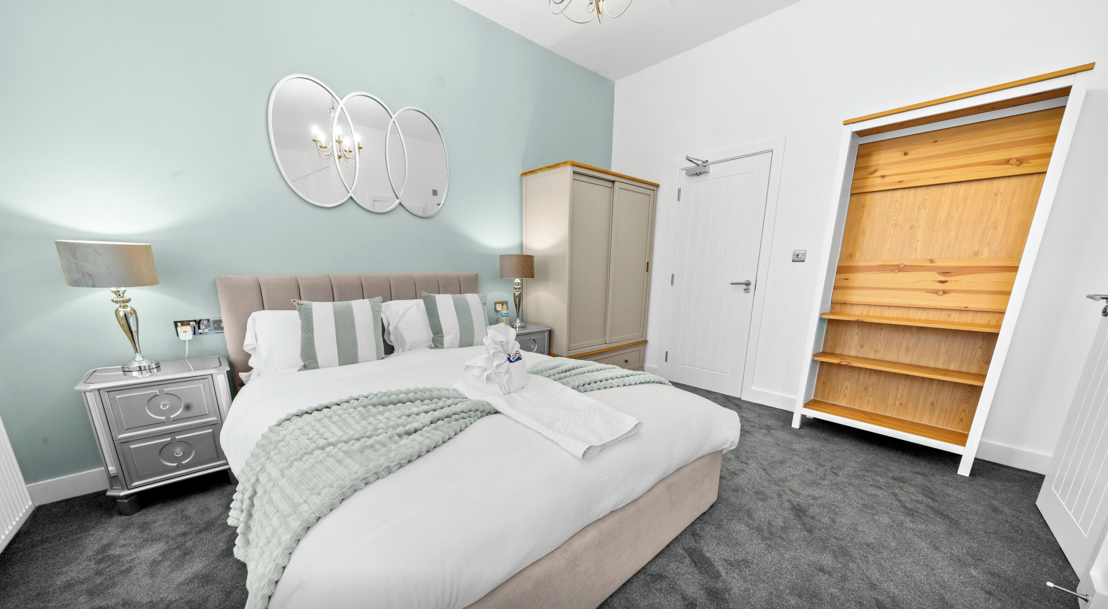 A bedroom with a bed, bedside tables, a wardrobe, and a mirror.