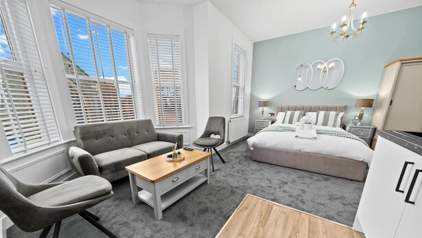 Een moderne slaapkamer met een sofa, fauteuil, nachtkastje en een bed.