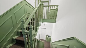 Een trap met groene leuningen en een bekleed landingsvlak.