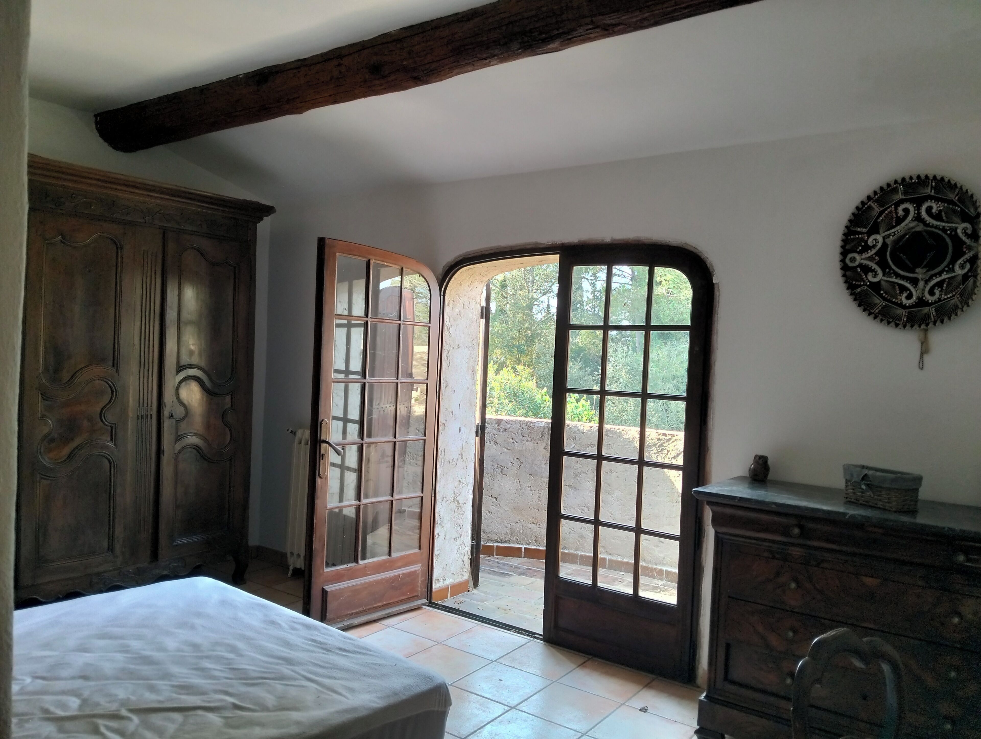 Une pièce comprenant un lit, une armoire en bois et une porte donnant sur l’extérieur.