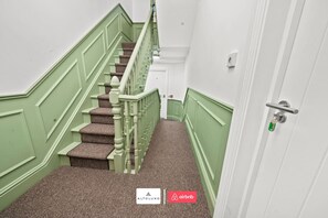 Een trap met groene wanden en beklede treden die naar een deur met sleutelgat leiden.