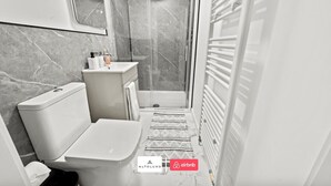 A modern bathroom with a toilet, sink, and shower. - Burnham-on-sea | Luxury | Families | Large Groups (Somerset)