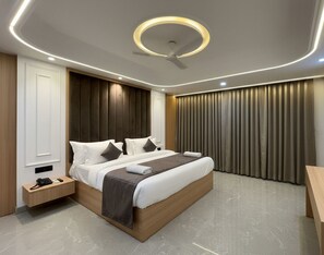 Een moderne slaapkamer met een groot bed, nachtkastjes, een plafondventilator en uitzicht buiten door gordijnen.