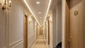 A long, well-lit hallway with marble flooring, doors on both sides, and wall sconces. - Narayana Grand Hotel (New Delhi)