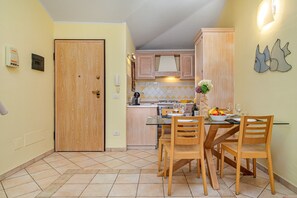 Una cocina funcional con armarios de madera, una mesa de comedor con sillas y una pequeña isla con un fregadero.