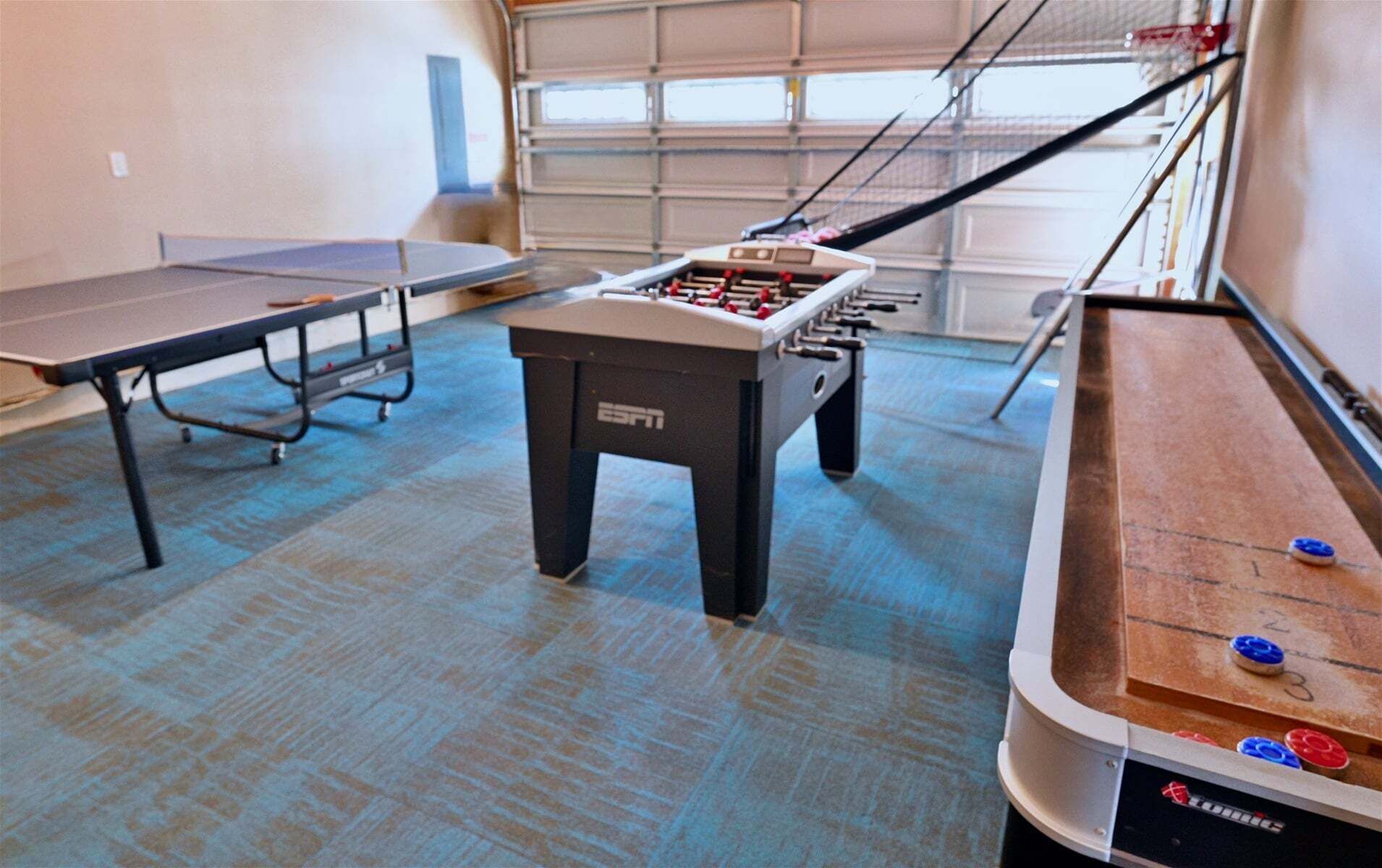 Een kamer met een tafelvoetbaltafel, een pingpongtafel en een biljarttafel.
