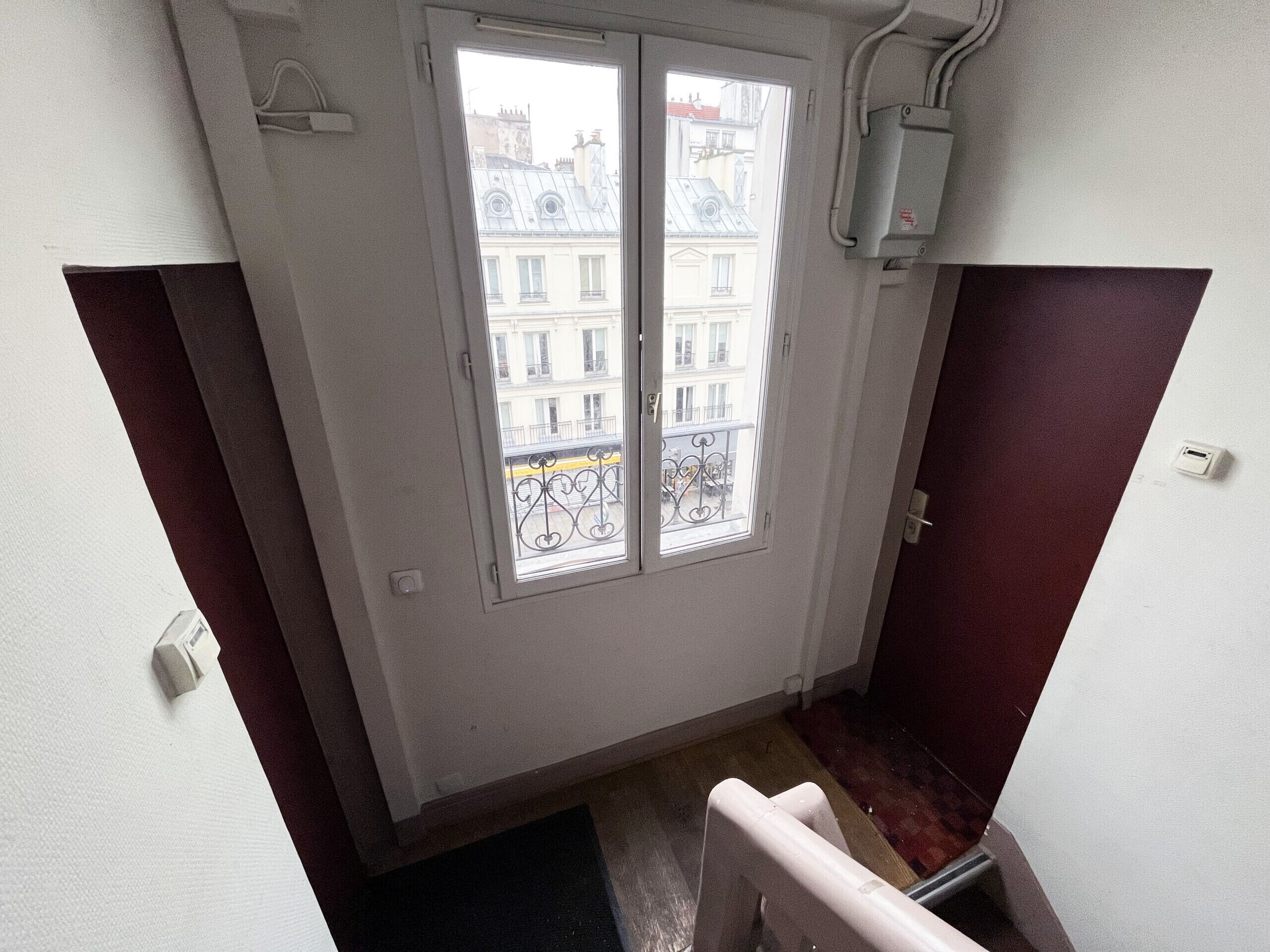 Un escalier étroit menant à un balcon d’où l’on peut admirer la vue sur les bâtiments.