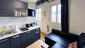 Eine moderne Küche mit dunklen Schränken, einem Holztisch und einem schwarzen Sofa.