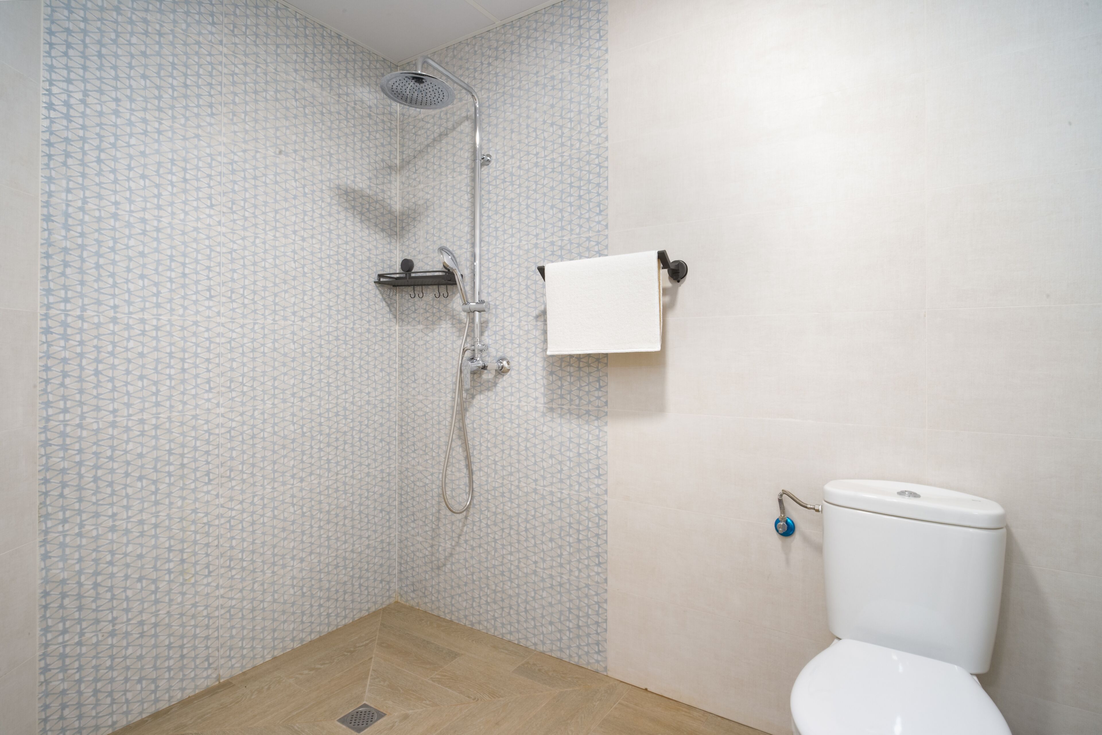 A bathroom with a shower, toilet, and patterned wall tiles.