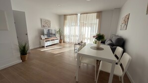Een moderne woonkamer met een eettafel, bank en een televisie op een wit meubel.