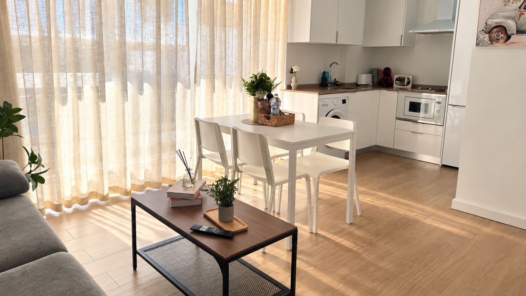 A modern living room with a sofa, a coffee table, and a dining area with chairs and a small table.