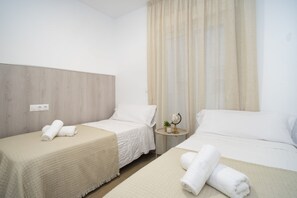A hotel room with two beds, a round table with a globe, and a power outlet on the wall. - Apartamento Don José 2Izq (Malaga)