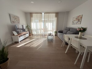 A modern living room with a TV, sofa, dining table, and potted plants. - Apartamento Don José 2Izq (Malaga)