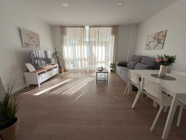 A modern living room with a TV, sofa, dining table, and potted plants. - Apartamento Don José 2Izq (Malaga)
