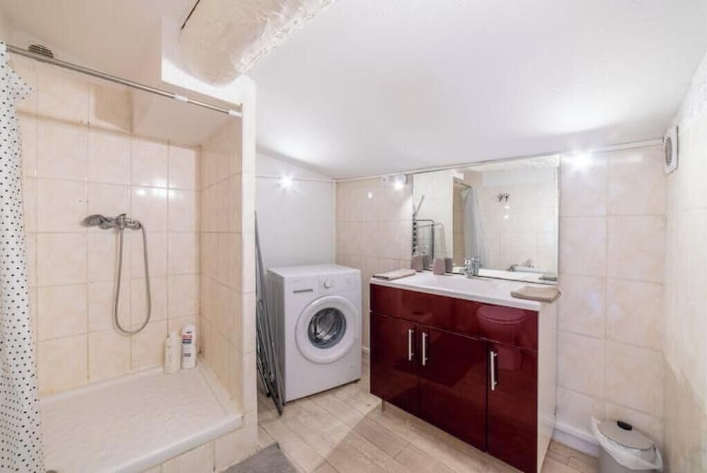 Un bagno con doccia, lavatrice, lavabo e specchio.