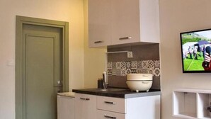 A compact kitchen with white cabinets, a countertop, a sink, and a tiled backsplash. - PeraHomes De (İstanbul)