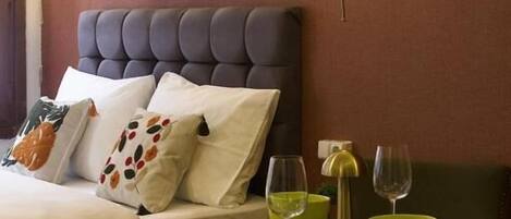 Una habitación de hotel con cama, mesitas de noche, un cuadro enmarcado y una lámpara de pared.