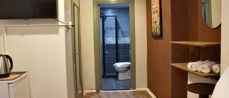 Ein Badezimmer mit Dusche, Toilette und einem Handtuchregal.