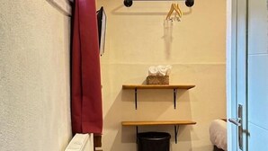 A narrow room with a radiator, a black trash bin, wooden flooring, and a door. - PeraHomes De (İstanbul)