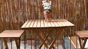 A wooden table with two chairs, a potted plant, and a bamboo fence in the background. - PeraHomes De (İstanbul)