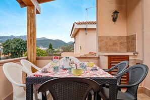 Mesa al aire libre con sillas, pared de azulejos y vistas a montañas.
