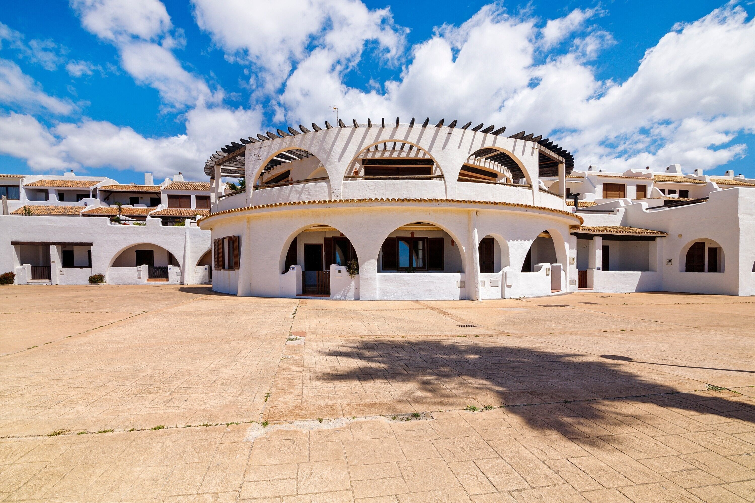 A courtyard with white buildings featuring arches and a central open space.