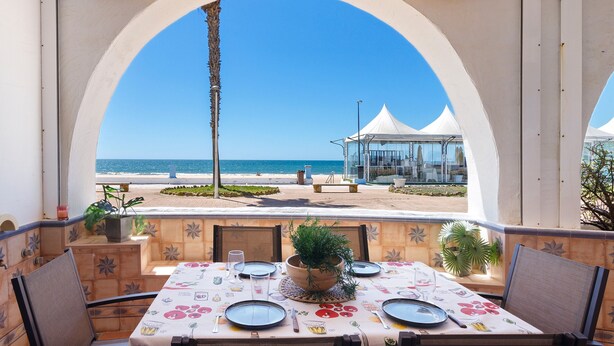 Mesa preparada para comer con vistas a la playa y el océano.