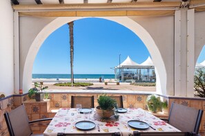 A table set for dining with a view of the beach and ocean. - Beachfront House in Matalascañas with Sea Views (Matalascañas)