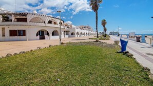 Un edificio frente al mar con ventanas arqueadas y una palmera.