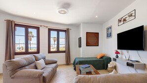 Una sala de estar con sofá, cama, televisor y ventana con vistas.