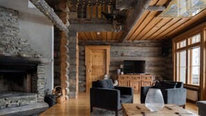 L’intérieur d’une cabane en rondins, avec une cheminée en pierre, des meubles en bois et un téléviseur.