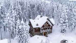 Une cabane en rondins entourée d’arbres couverts de neige.