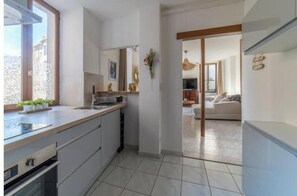 Eine moderne Küche mit großem Fenster, einer Spüle und Blick in einen Wohnbereich mit Sofa und Esstisch.