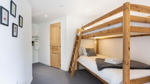 A bunk bed room with a wooden ladder, white bedding, and a door with a wooden panel. - Chalet in Paradiski With Spa and Mountain Views (Peisey-Nancroix)