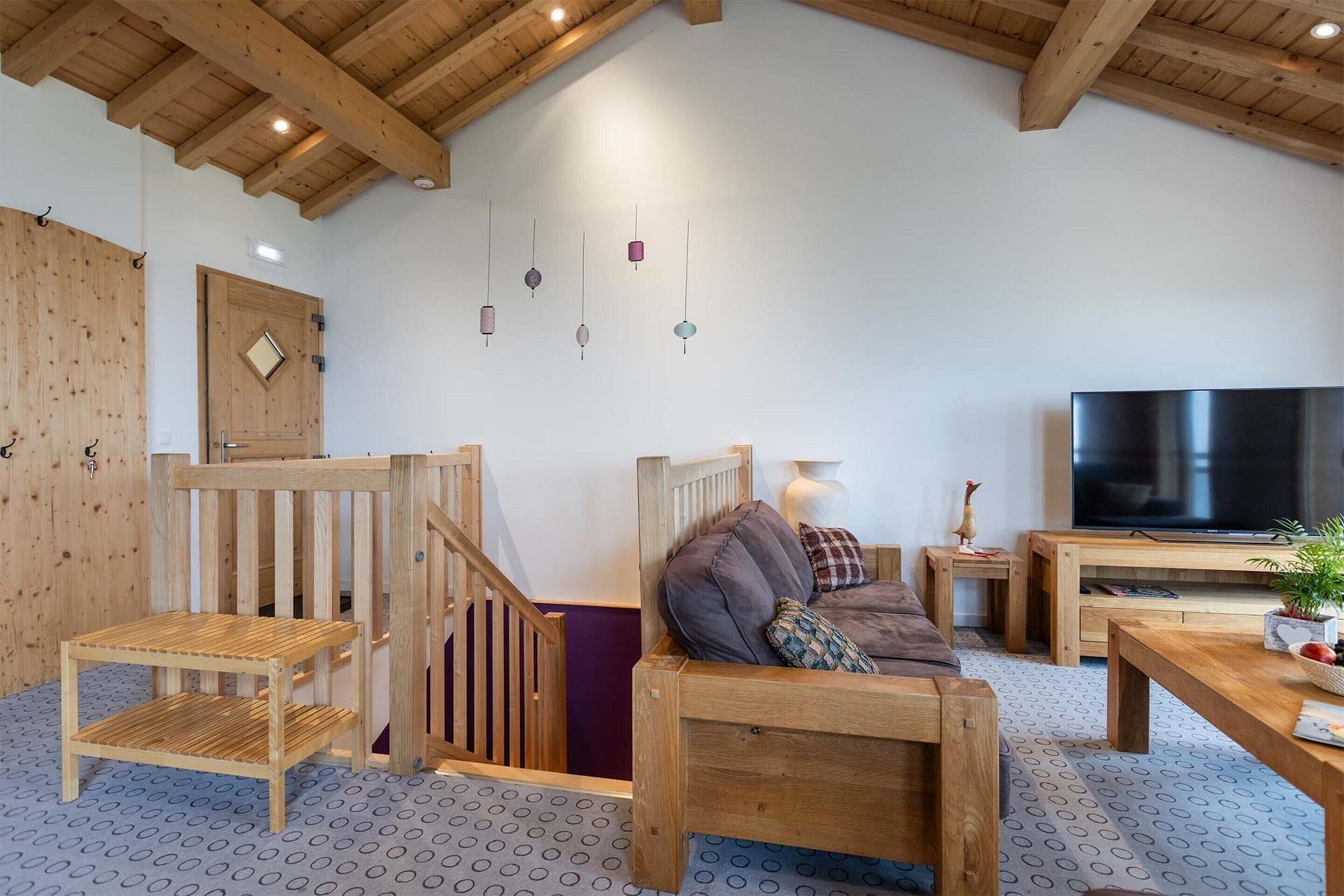 Un intérieur en bois avec un canapé, un téléviseur et un escalier.