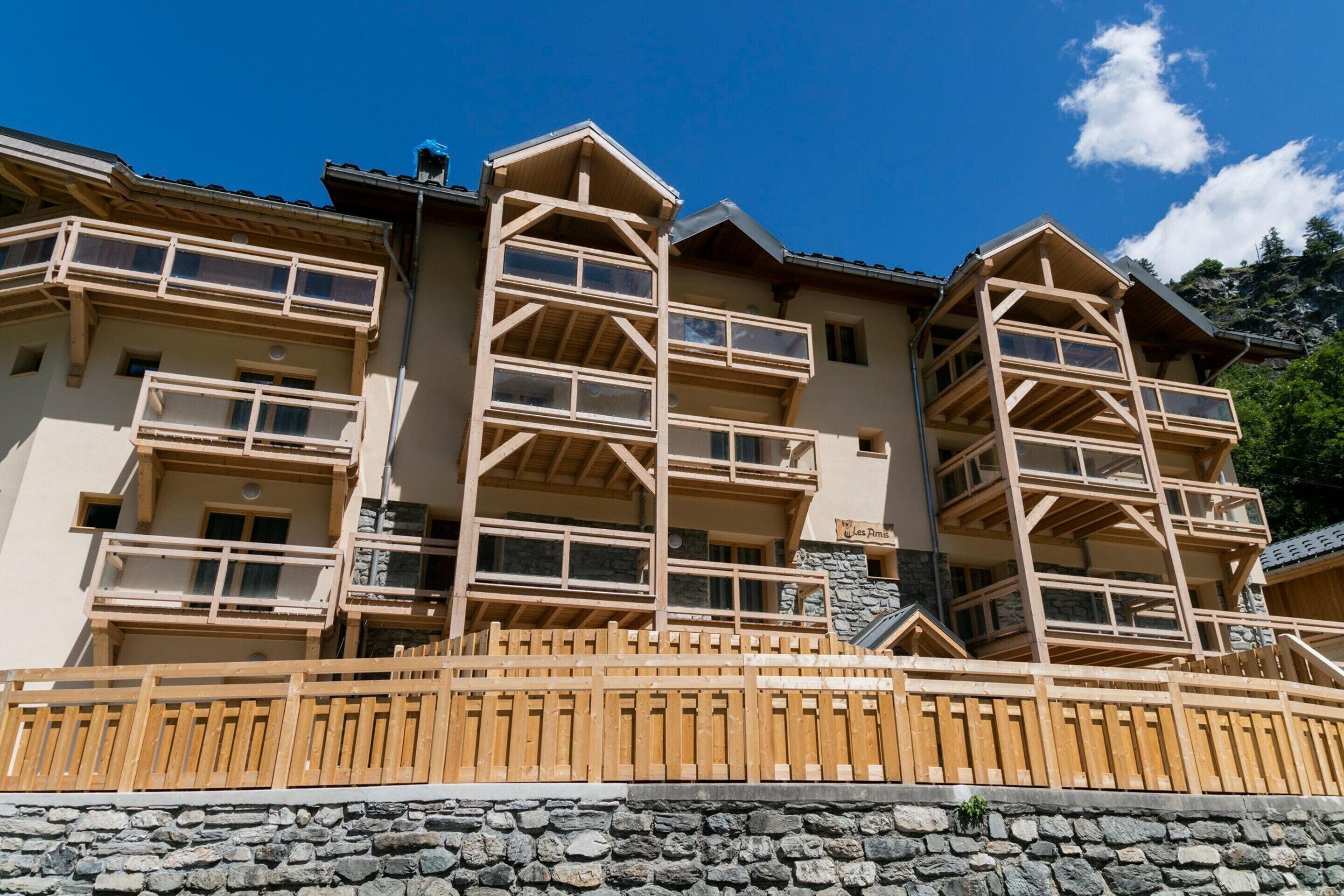 Un edificio de varios pisos con balcones, base de piedra y barandillas de madera.