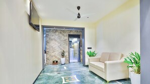 A lobby with a marble floor, a sofa, potted plants, and an elevator.