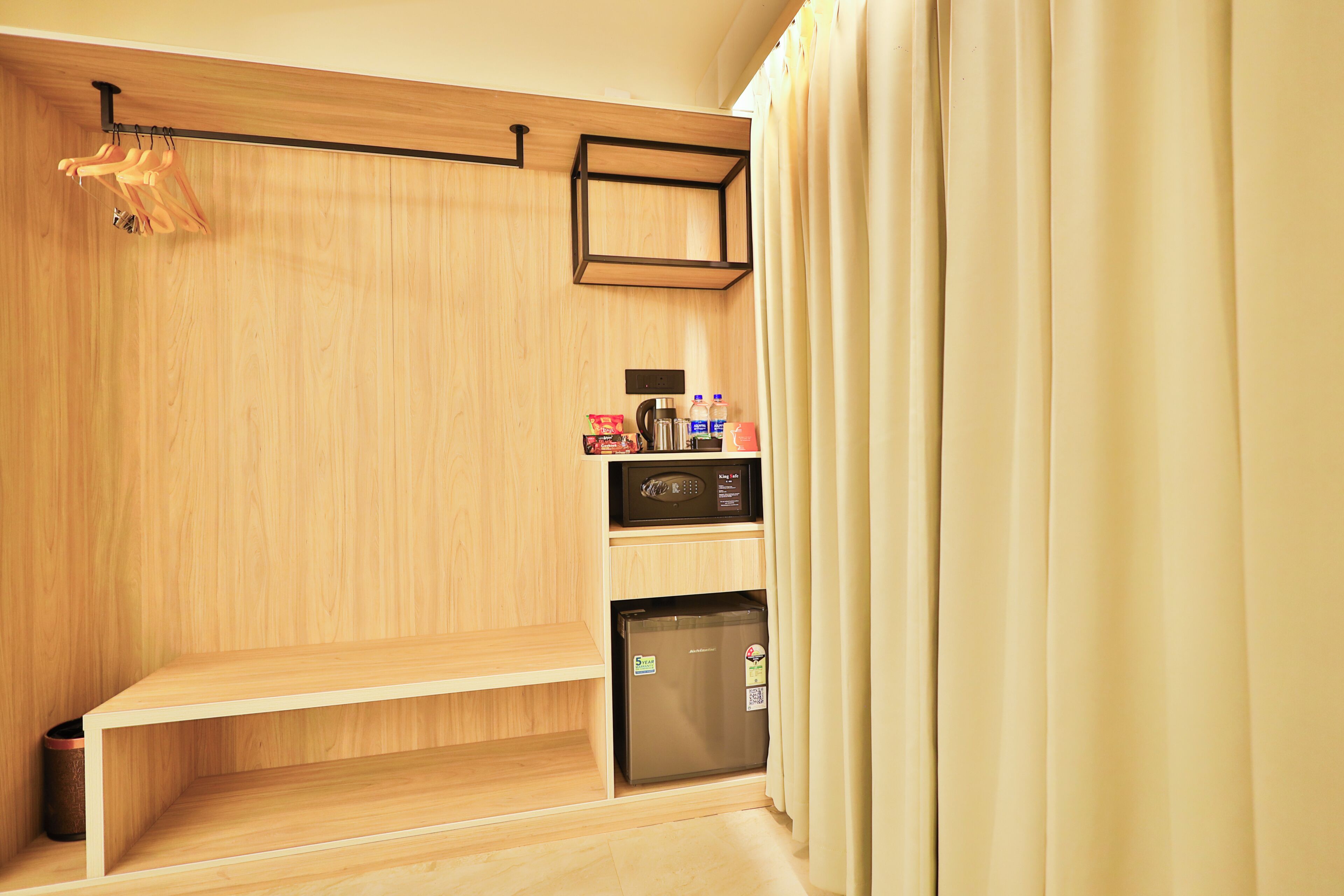 A compact kitchenette with a microwave, refrigerator, and a small shelf with items.