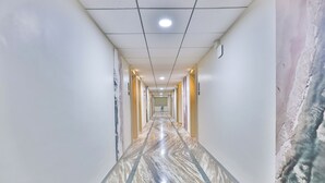 A hallway with marble flooring, recessed lighting, and a view of the ocean through a large window.