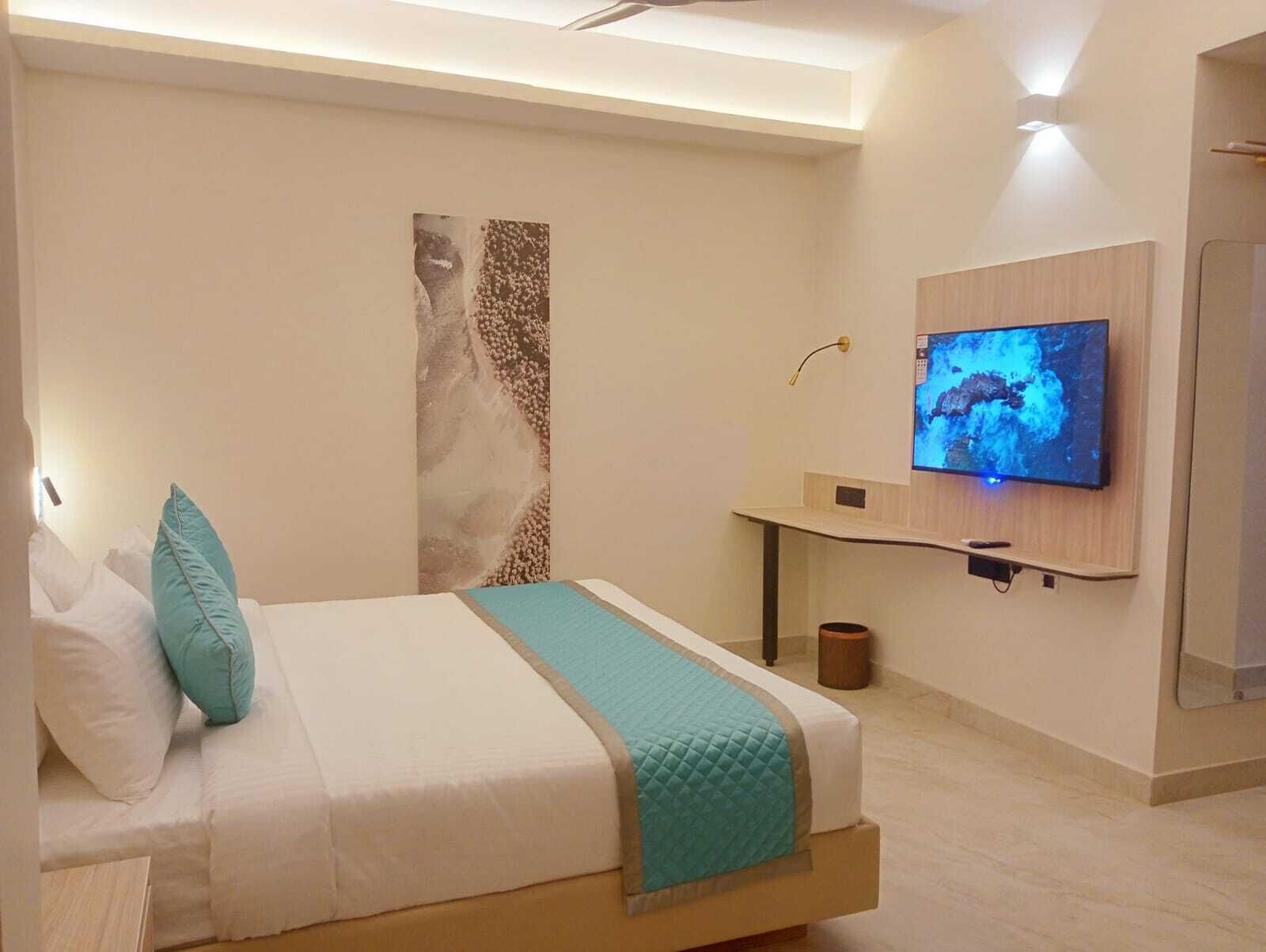 Une chambre à coucher moderne avec un lit, un téléviseur fixé au mur et une grande œuvre d’art accrochée au mur.