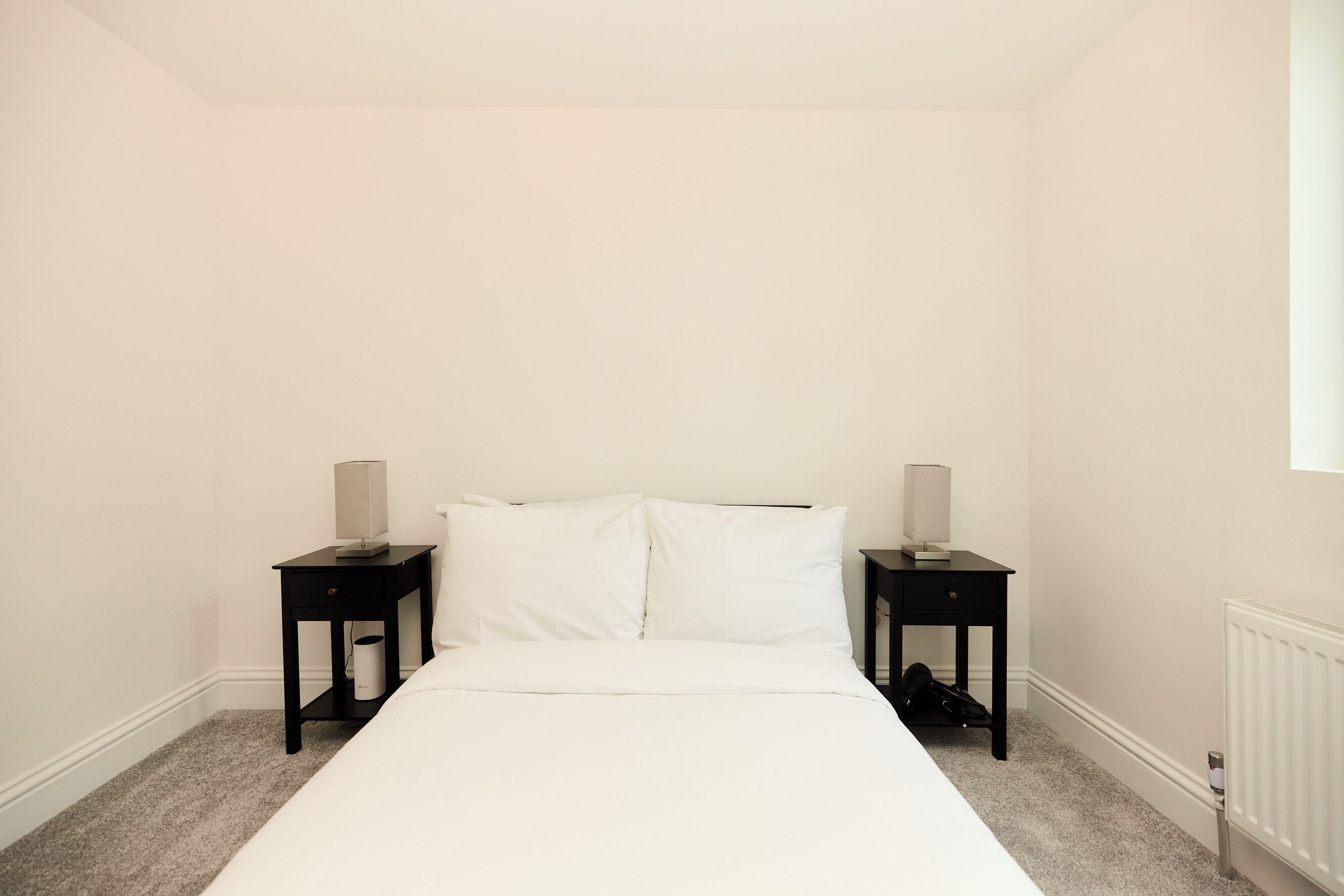 Een slaapkamer met een bed, twee nachtkastjes en een radiator.